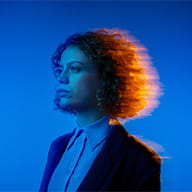 Una donna con i capelli ricci in piedi davanti a uno sfondo blu