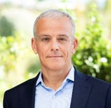 un hombre con un traje de pie frente a los arbustos