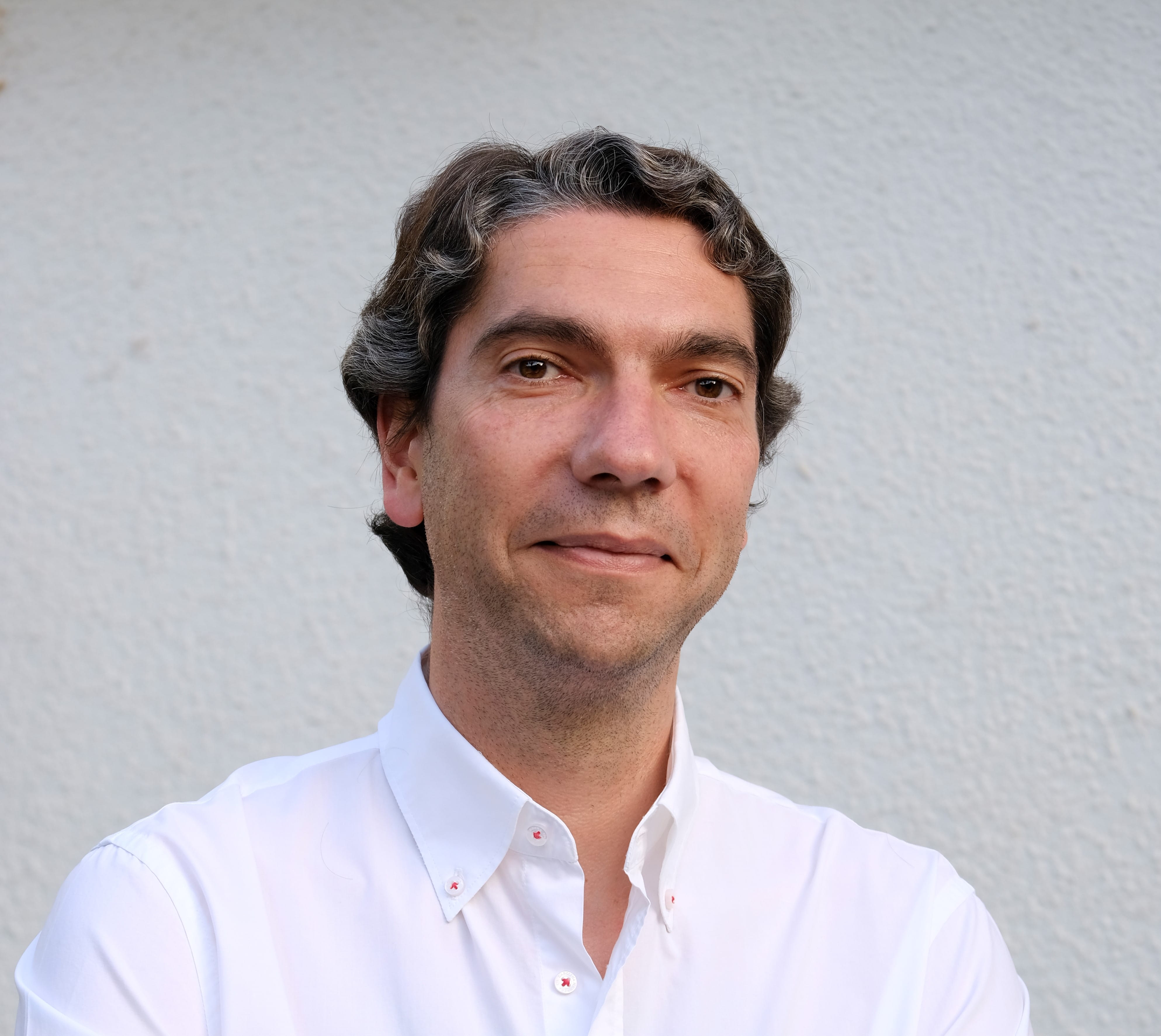 Un hombre con una camisa blanca de pie frente a una pared