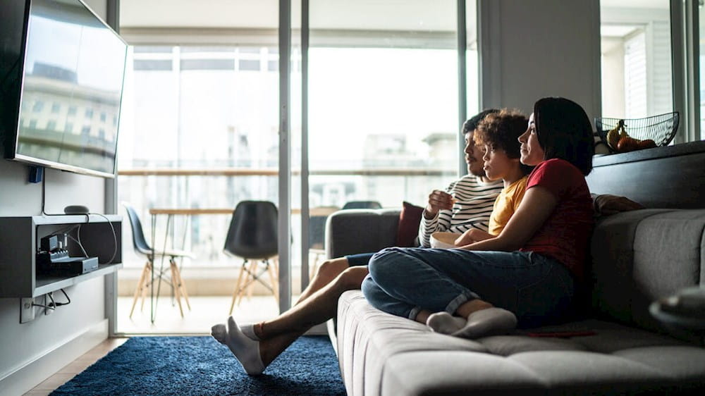 two women sitting on a couch watching tv
