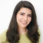 a young woman smiling in front of a white wall