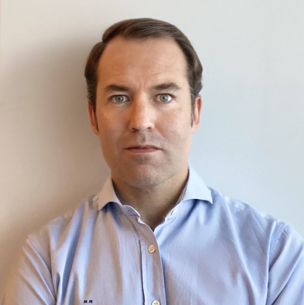 a man in a blue shirt leaning against a wall