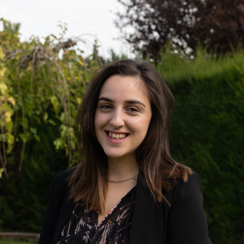 a young woman smiling in front of bushes