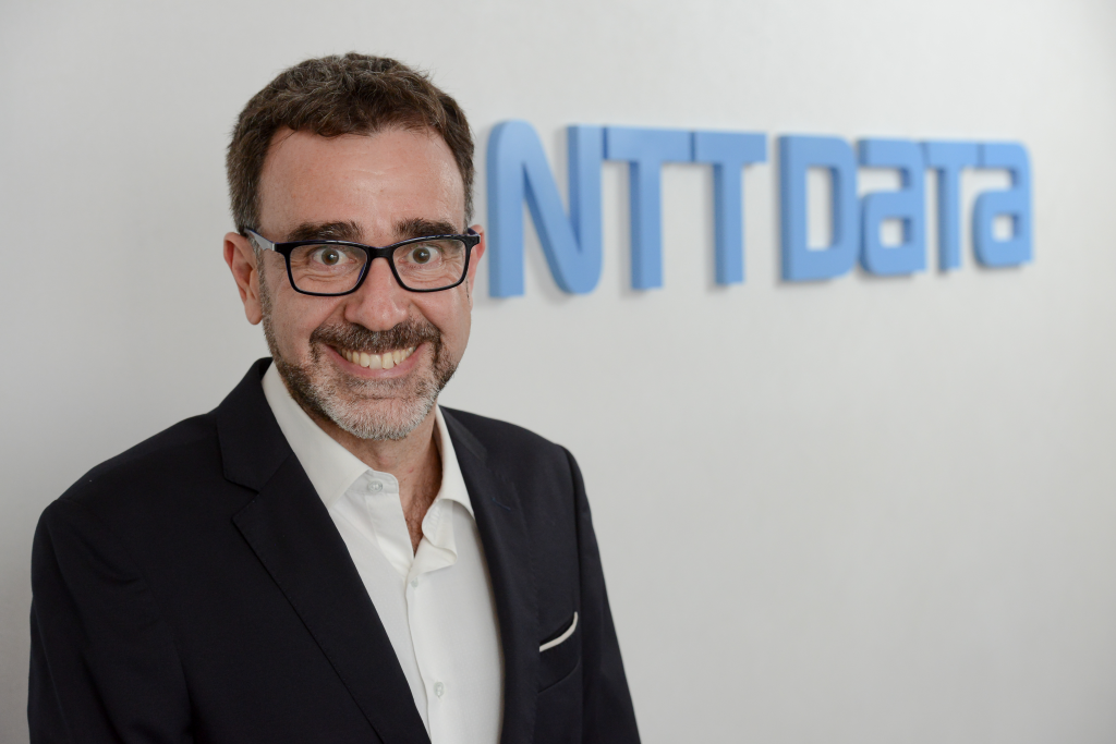 Um homem sorrindo em frente ao logotipo de dados da NTT