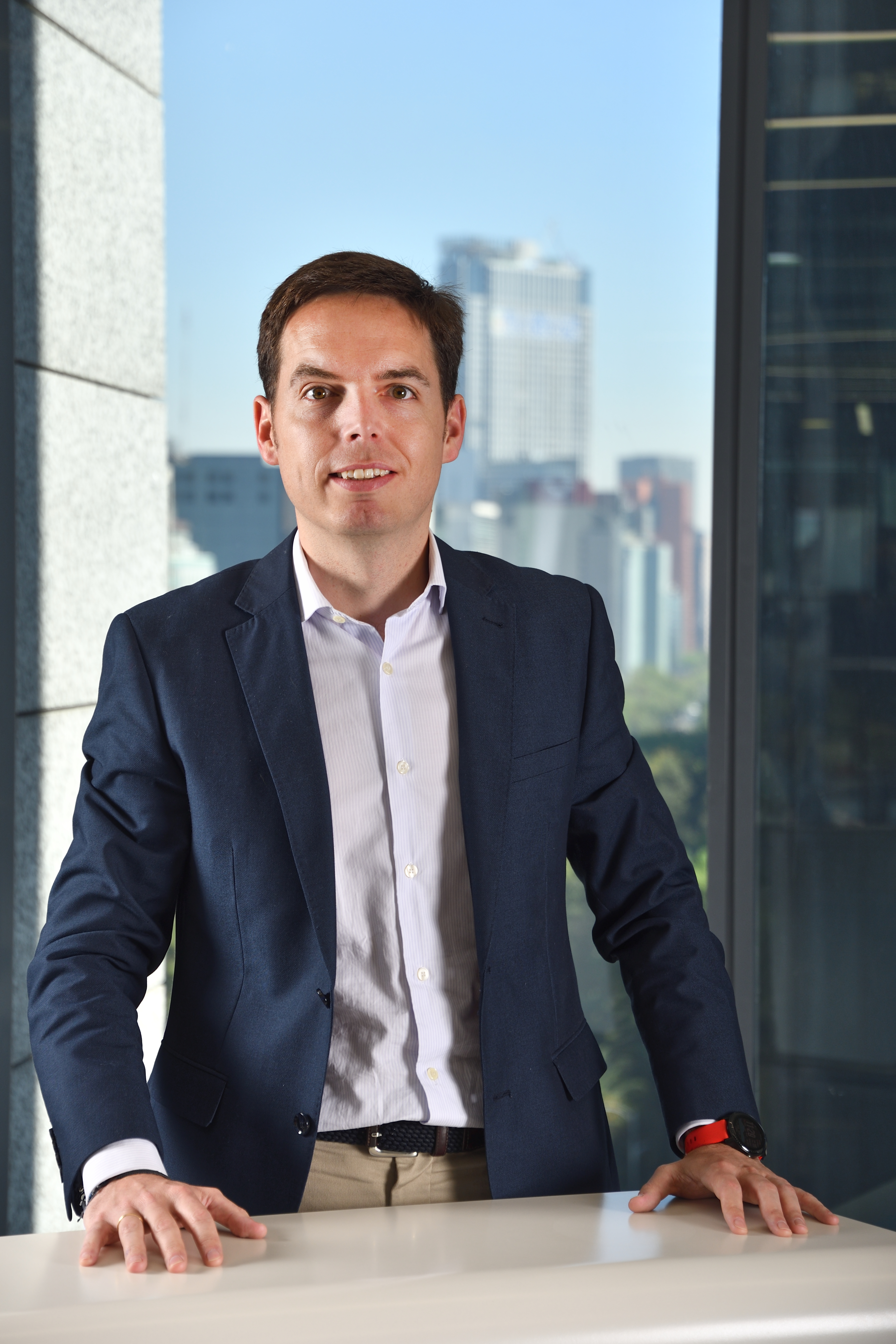 un hombre con un traje apoyado contra un escritorio