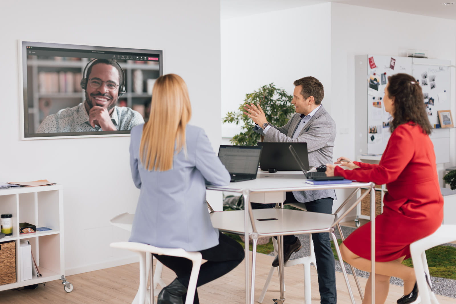 Eine Gruppe von Personen, die an einem Tisch sitzen und eine Videokonferenz sehen