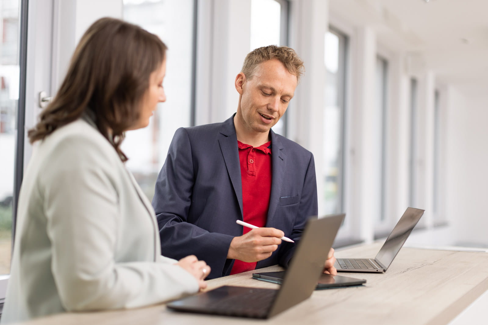 Ein Mann und eine Frau, die in einem Büro an Laptops arbeitet