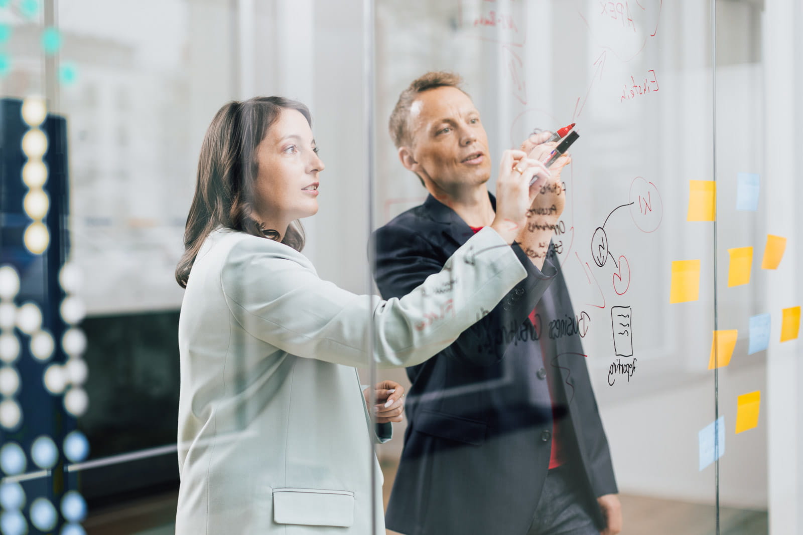 Ein Mann und eine Frau, die an einer Glaswand schreibt
