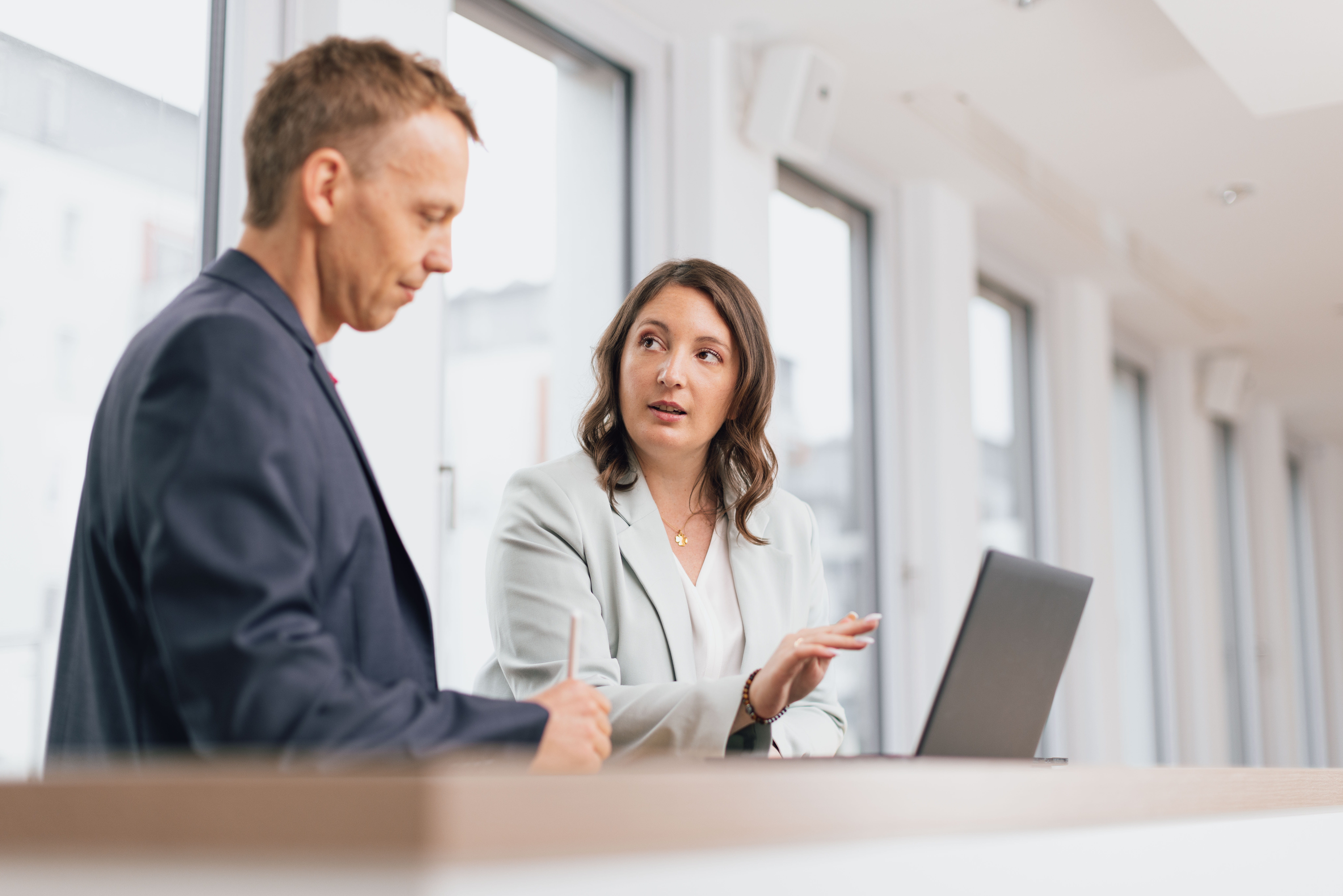 Zwei Geschäftsleute, die an einem Tisch in einem Büro sprechen