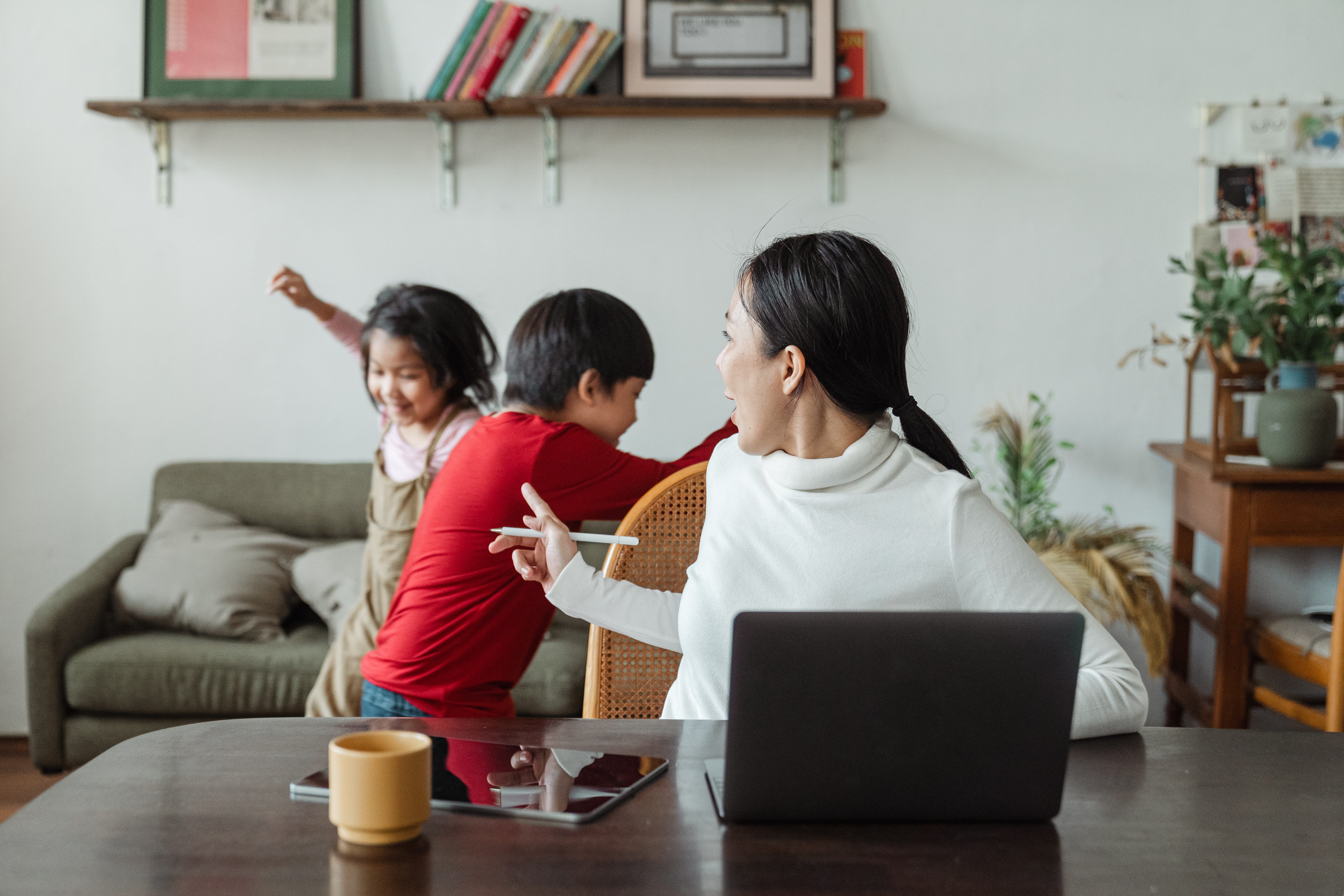 Eine Frau und ihre Kinder spielen mit einem Laptop im Wohnzimmer