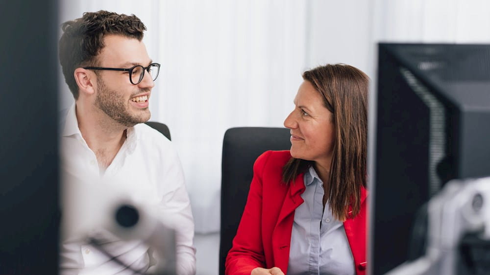 Ein Mann und eine Frau, die vor einem Computer spricht