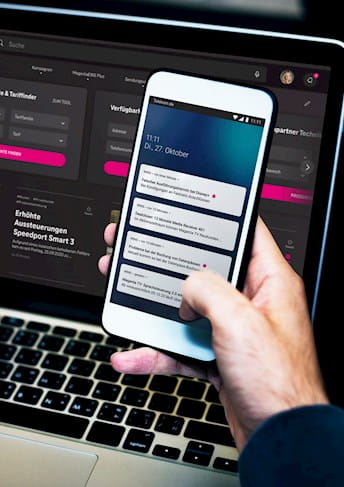 NTT DATA Success Story Telekom - ein Mann bedient eine App auf seinem Smartphone und auf einem Laptop