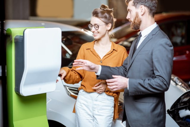 Ein Mann und eine Frau, die neben einer Autoladestation steht