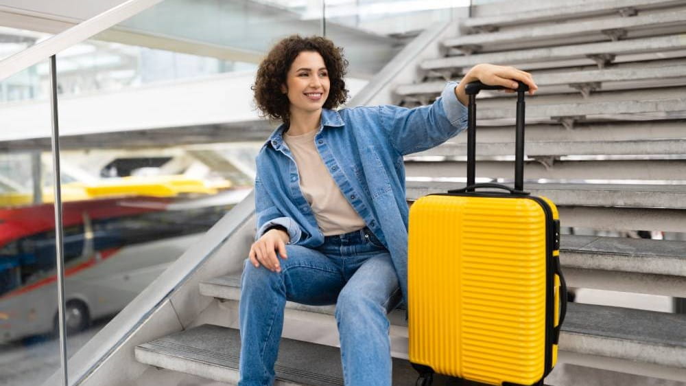 beautiful-young-woman-with-luggage-sitting-on-stai