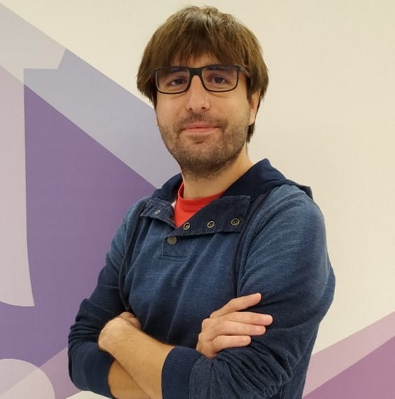 un hombre con vasos parados frente a una pared morada