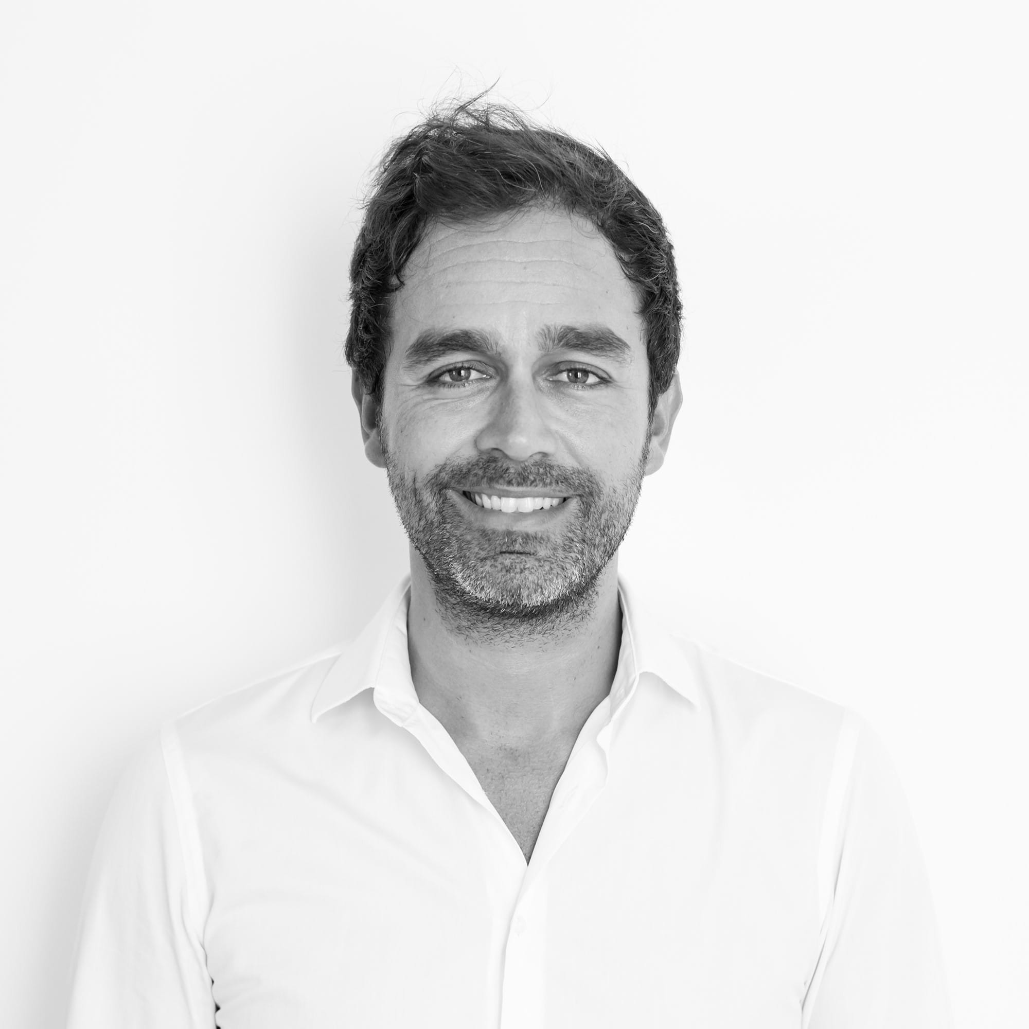 Un hombre sonriendo con una camisa blanca