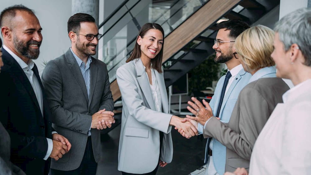 Gruppo di professionisti che concludono un accordo, due si stringono la mano