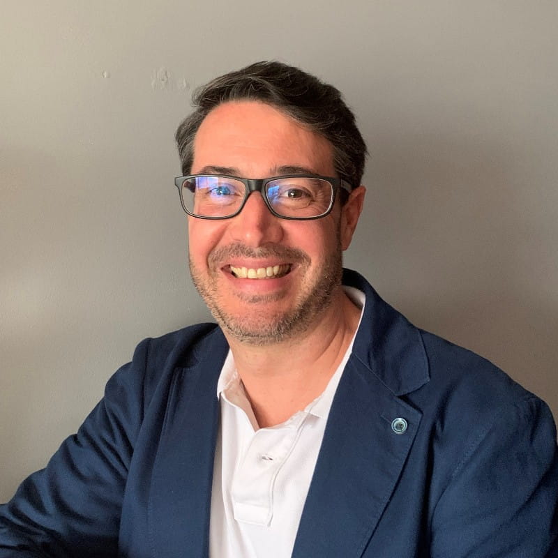 Un hombre sonriente con vasos y una chaqueta azul