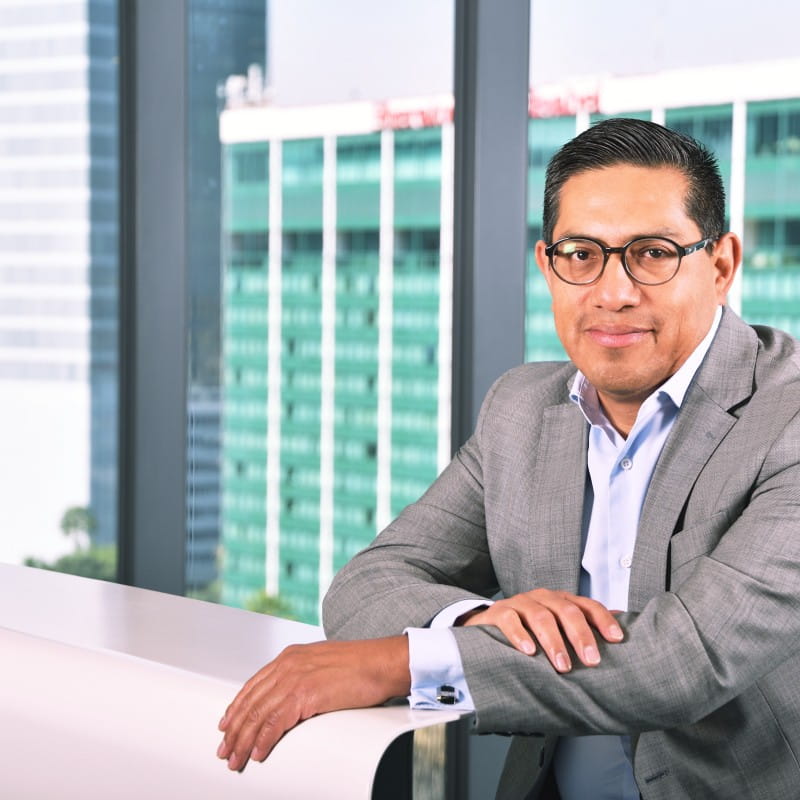 un hombre con anteojos apoyados contra una pared