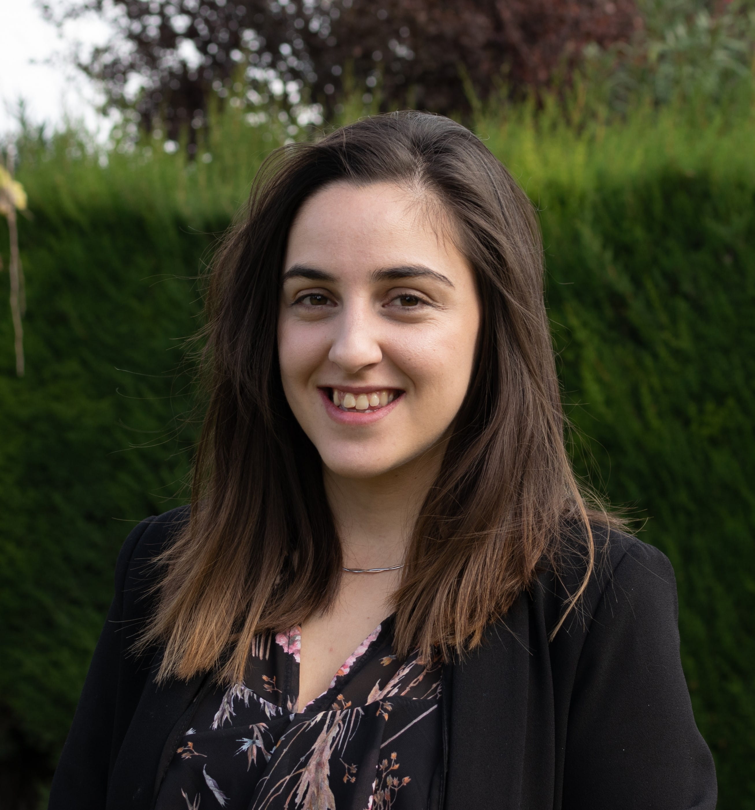 una mujer sonriendo frente a los arbustos
