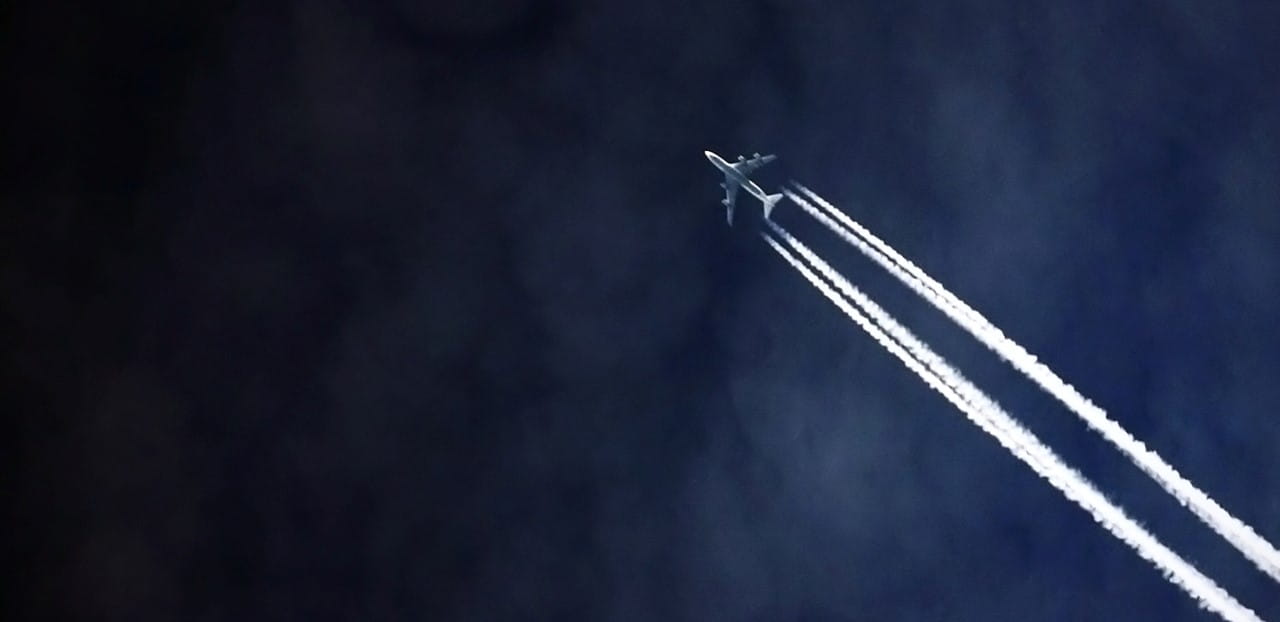 un avión volando por el cielo con estelas
