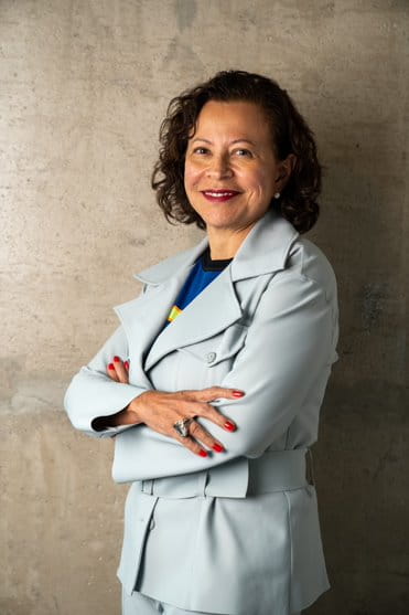 una mujer con un traje gris con los brazos cruzados