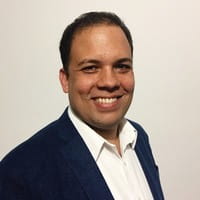 un hombre sonriendo frente a una pared blanca