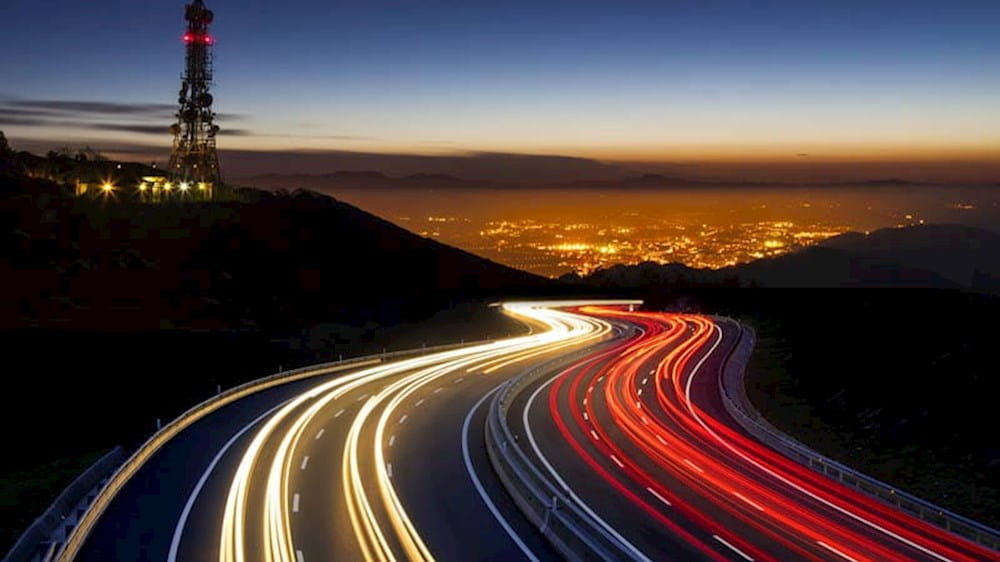 long exposure of a highway at night with a tv tower in the background