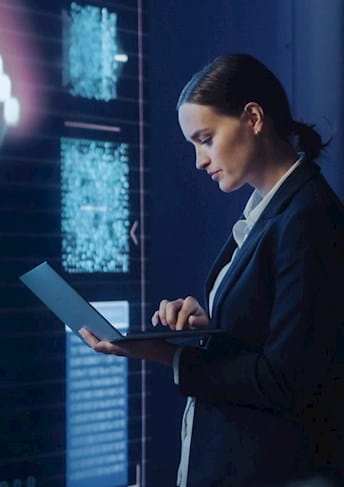 Una donna che usa un laptop davanti allo schermo di un computer
