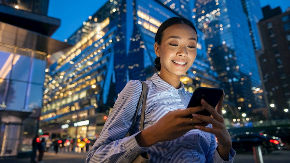 woman smiling and walking with a device in her hands