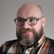 a bald man wearing glasses and a plaid shirt