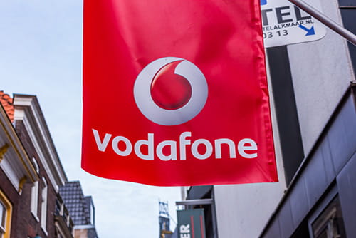 a red vodafone sign hanging from a building