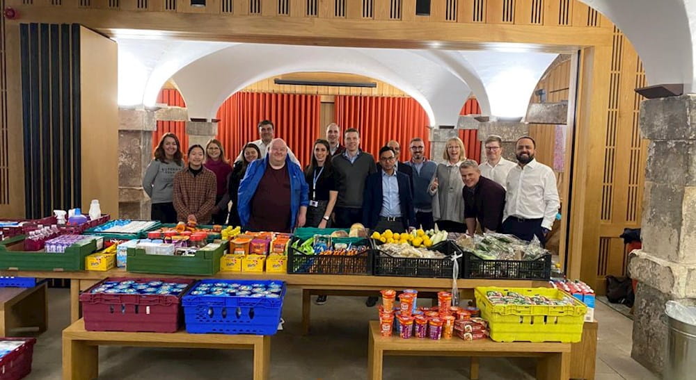 A table of fruit and vegetables with a group of people behind