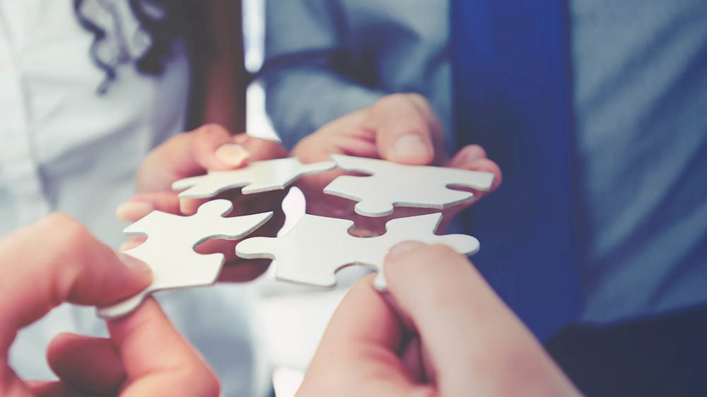 Four people holding puzzle pieces representing governance